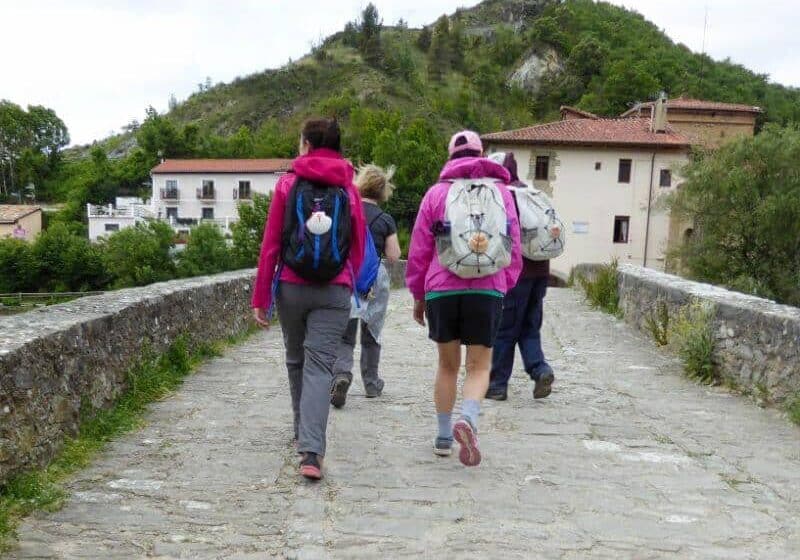 pilgrims walking the Camino on a bridge