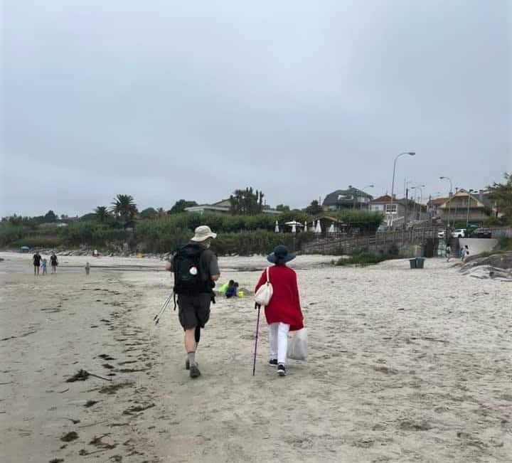 a picture of 2 pilgrims walking along the beach