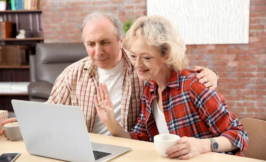 Elderly couple reviewing travel plans on laptop for Camino pilgrimage.